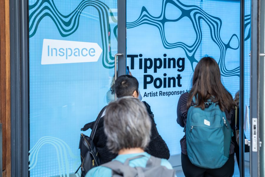 Photograph of 3 people walking through the Tipping Point exhibition entrance.